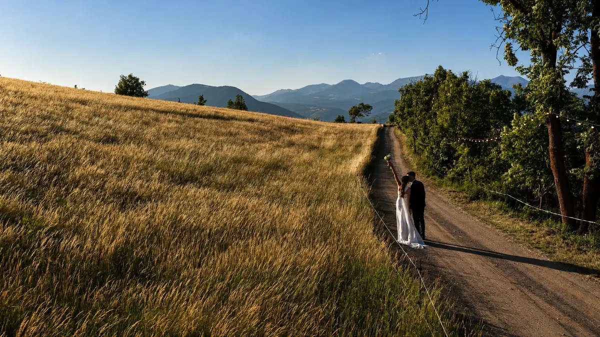 Pareja de novios paseando por un camino entre campos al atardecer