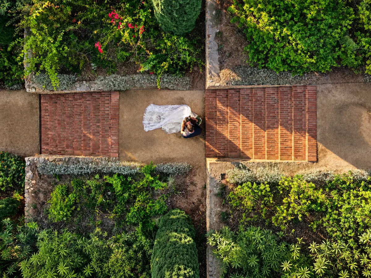 Novios en un camino entre jardines vistos desde arriba