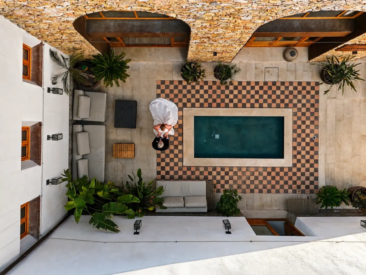 Novios junto a una piscina en un patio, vistos desde arriba
