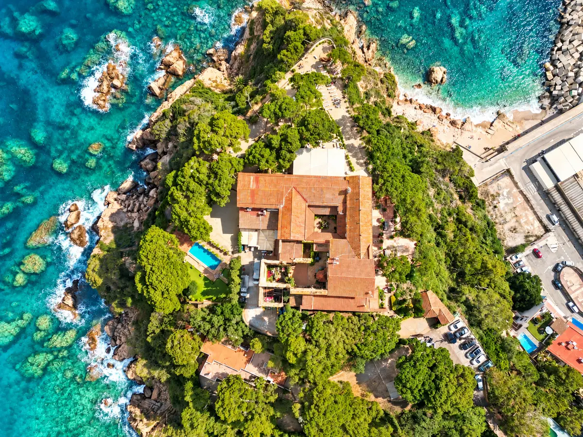 Casa entre rocas y aguas turquesas en la Costa Brava vista desde arriba