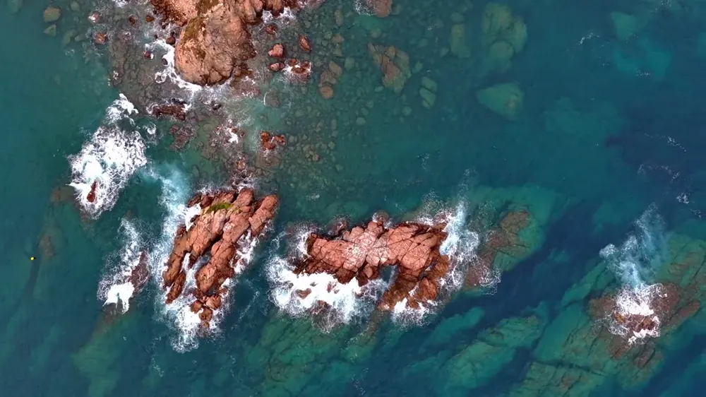 Vista cenital de rocas y aguas turquesas de la costa
