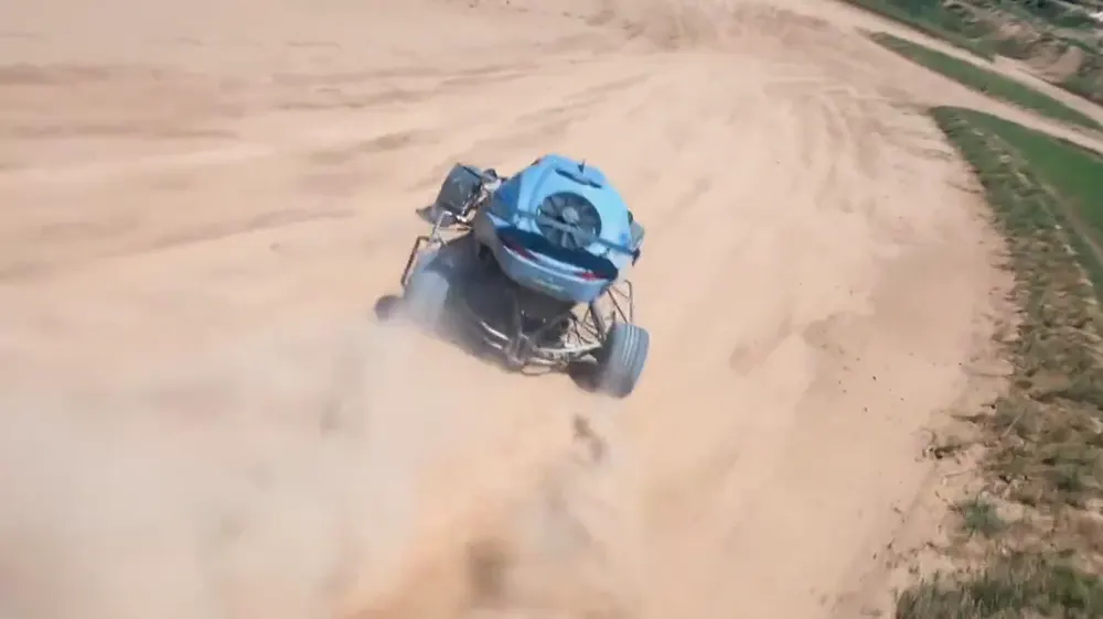 Buggy levantando polvo en un camino de tierra visto desde un dron FPV