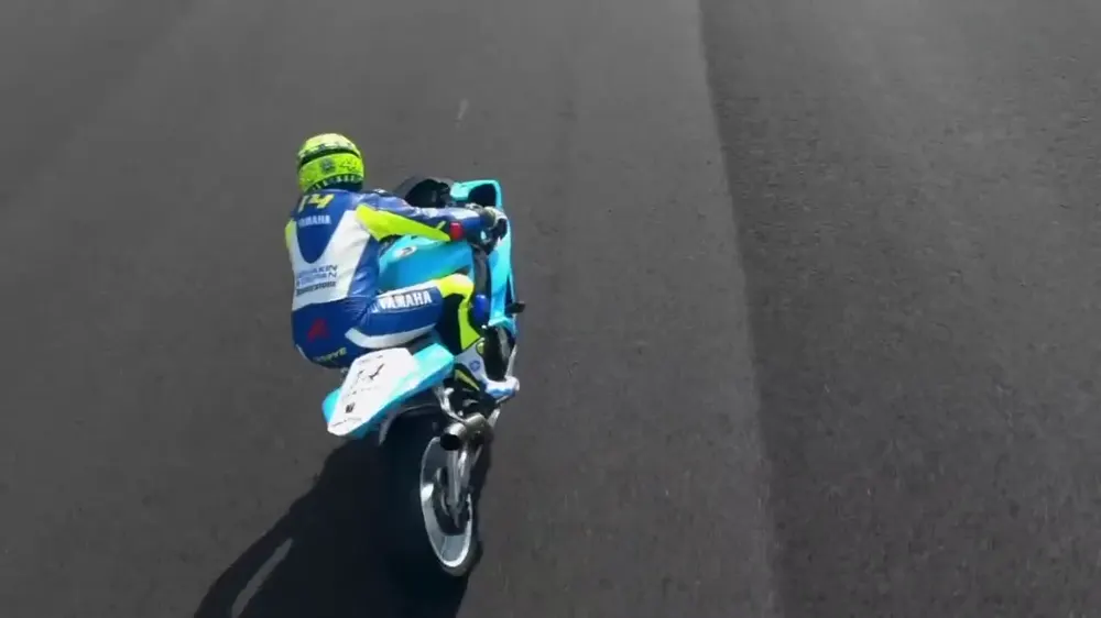 Moto de carreras levantando la rueda delantera en un circuito, vista desde un dron FPV