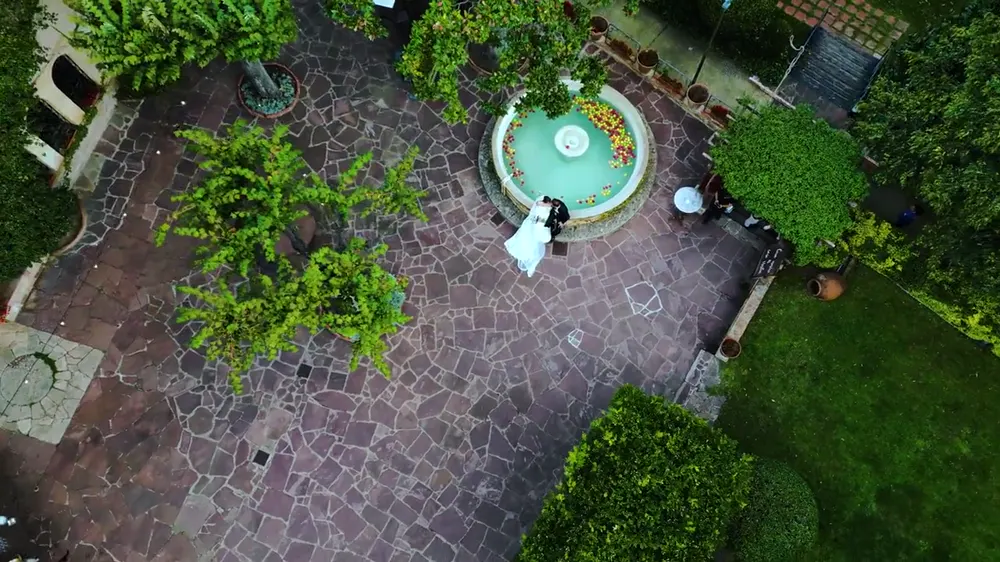 Vista aérea de unos novios junto a una fuente en un patio